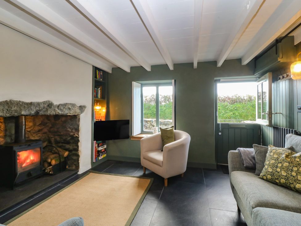 A living room with a fireplace and bookshelves at Seren Fach in Pwllheli