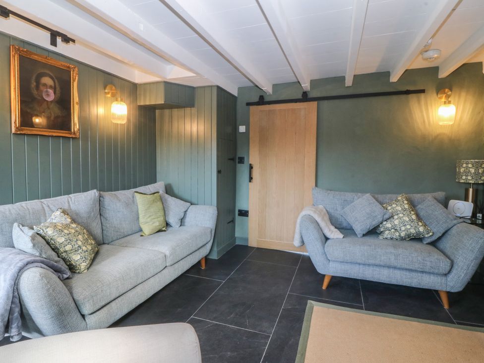 A living room with sofas and a painting at Seren Fach in Pwllheli