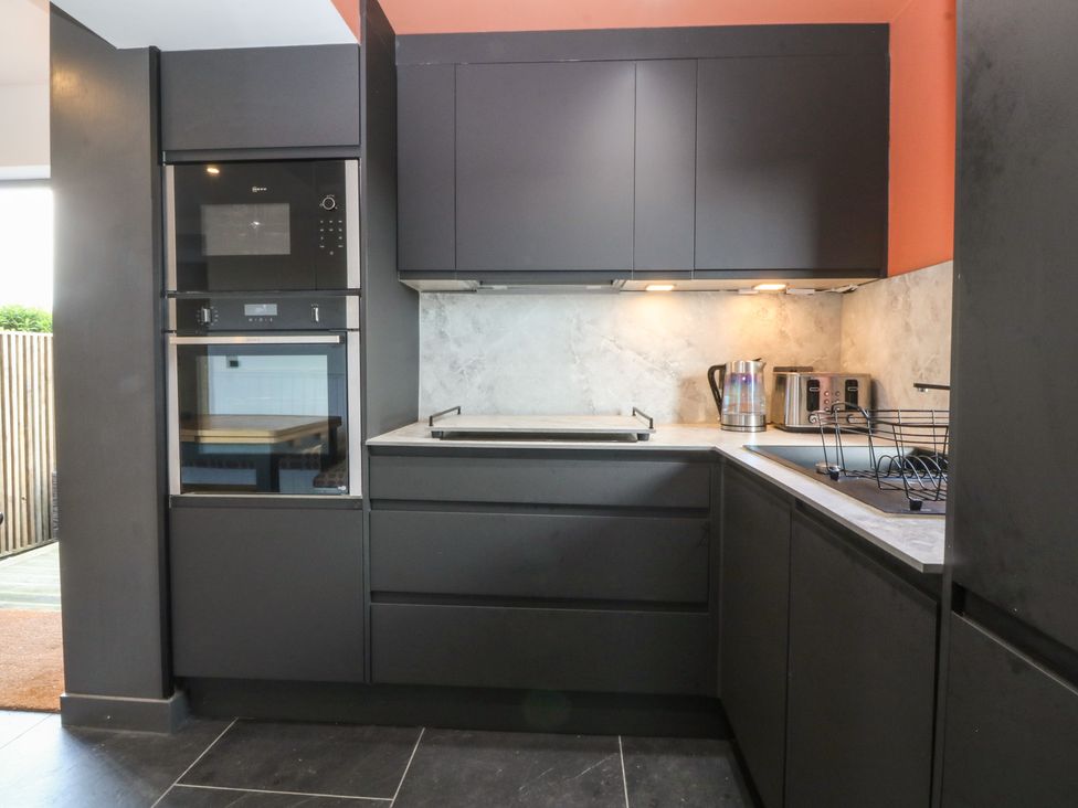 A kitchen with built-in appliances and cabinets at Seren Fach in Pwllheli