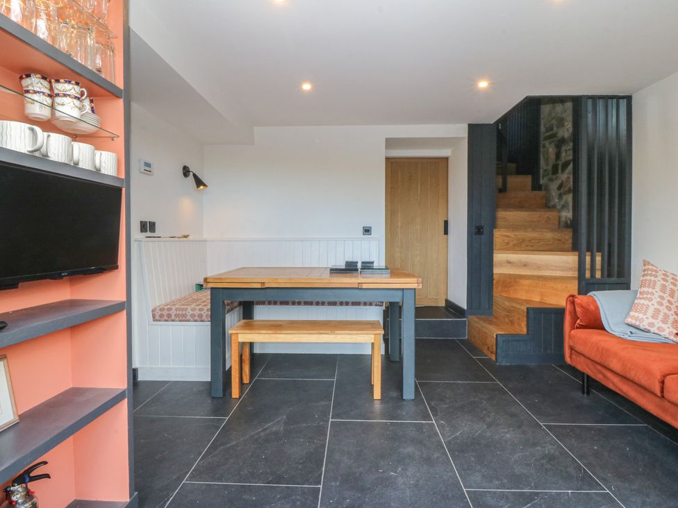 A dining room with a table and sofa at Seren Fach Pwllheli