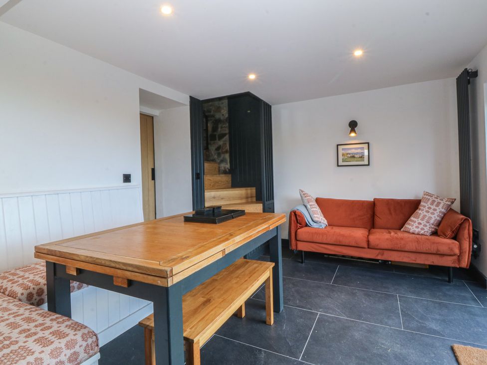 A living room with a wooden table and a sofa at Seren Fach in Pwllheli