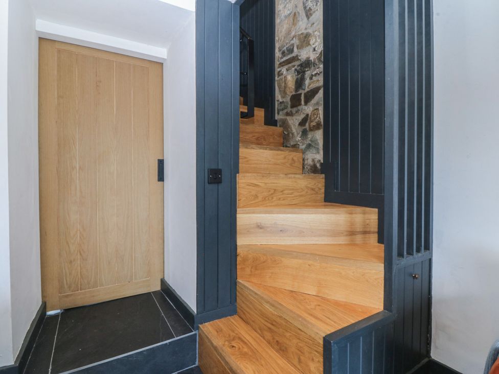 A staircase with wooden steps and a wooden door at Seren Fach Pwllheli