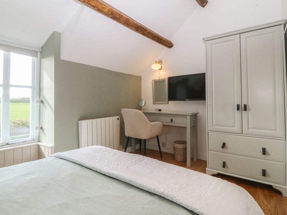 A bedroom with a bed, wardrobe, desk, and chair at Seren Fach in Pwllheli