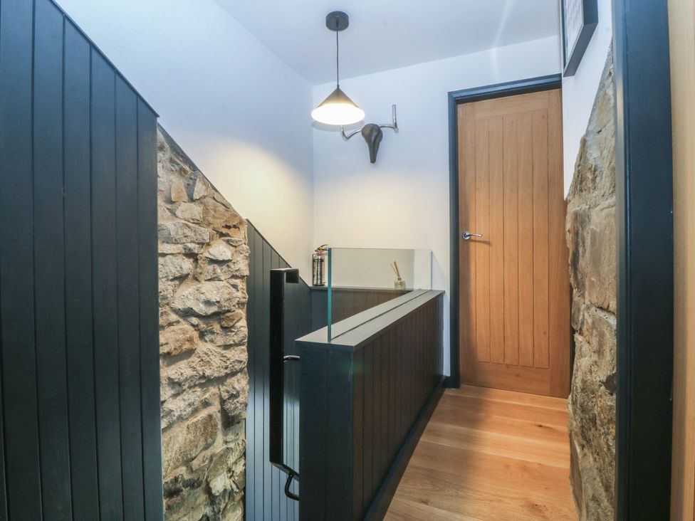 A staircase leading to a door in a hallway at Seren Fach in Pwllheli