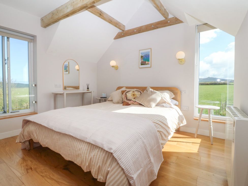 A bedroom with a bed and a mirror at Seren Fach in Pwllheli