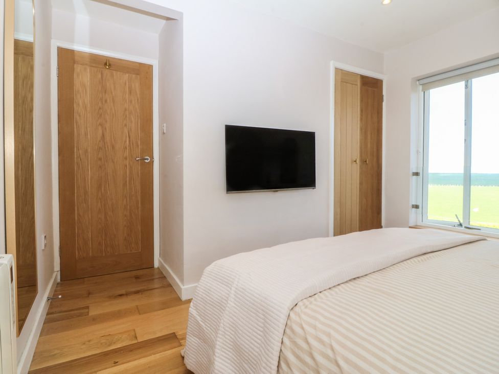 A bedroom with a bed and television at Seren Fach in Pwllheli
