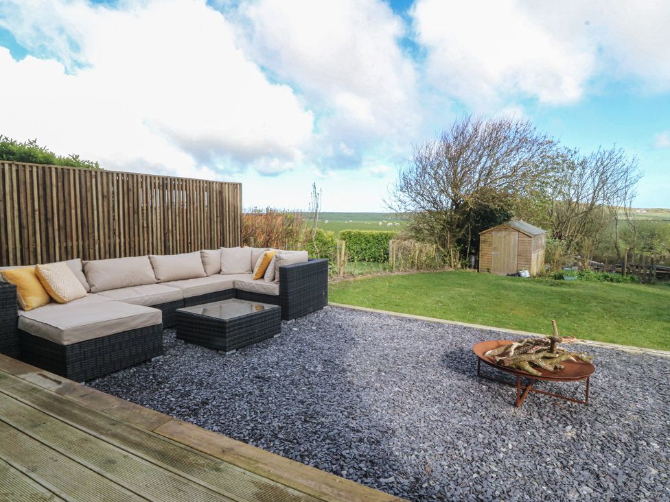 A garden with a sectional sofa and fire pit at Seren Fach in Pwllheli