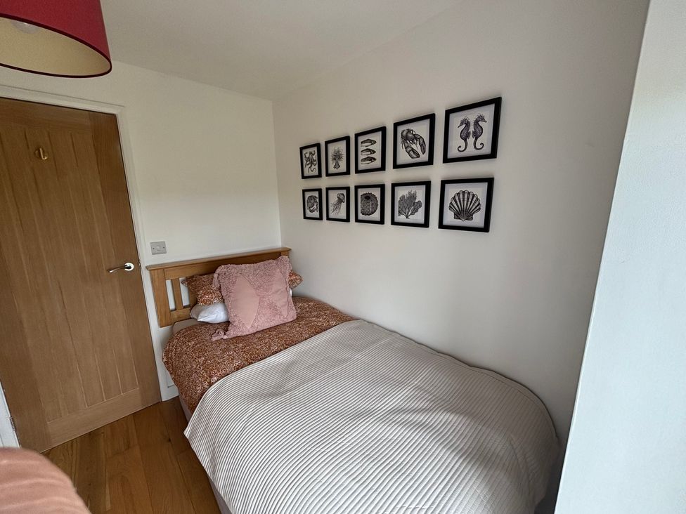 A bedroom with a bed and wall art at Seren Fach near Aberdaron