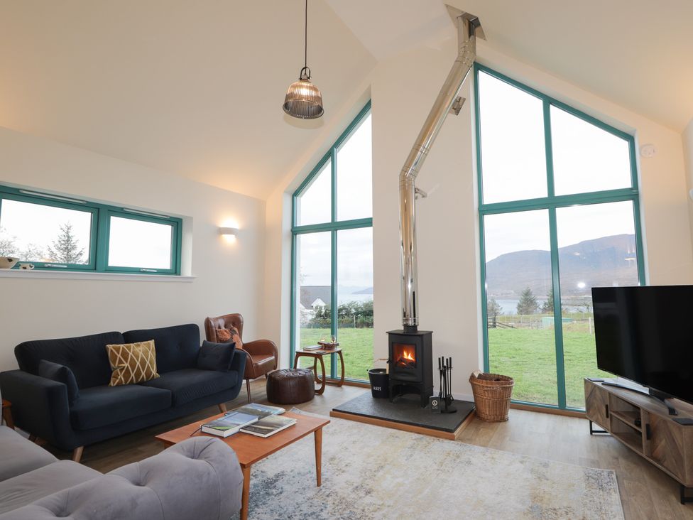 A living room with a sofa, coffee table, and wood stove at Sonas in Strathcarron