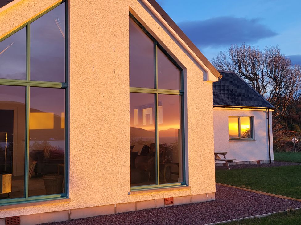 An exterior view of a house with large windows and reflections at Sonas, Lochcarron