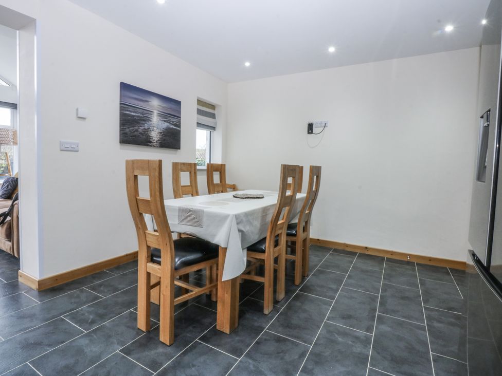 A dining room with a table and chairs at Benlli in Pwllheli