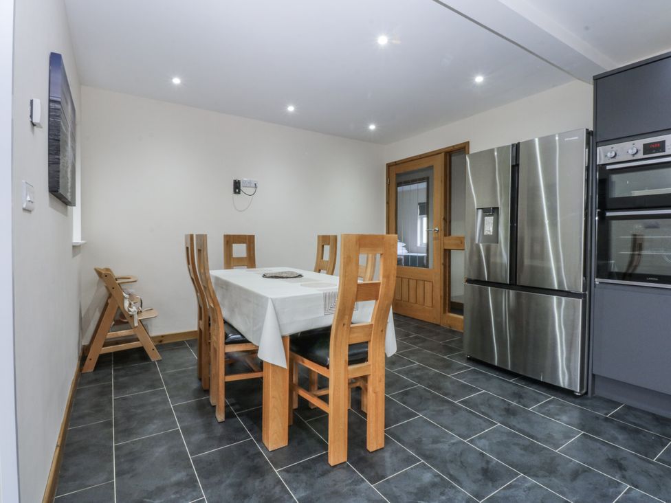 A kitchen with a dining table and chairs at Benlli in Pwllheli