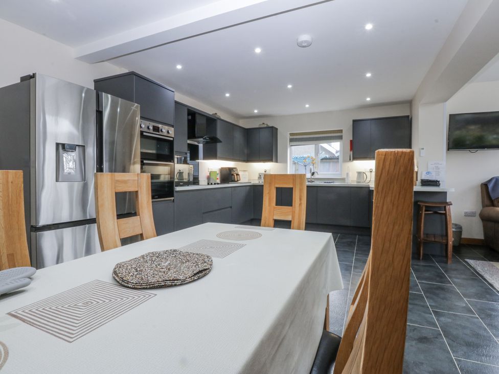 A kitchen with a table and chairs at Benlli in Pwllheli