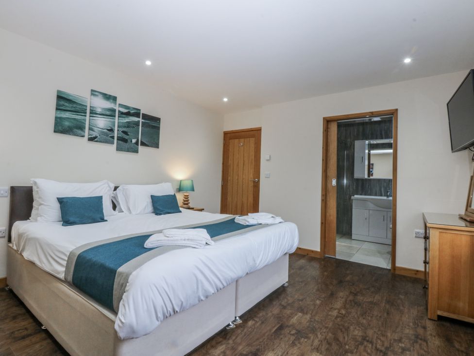 A bedroom with a bed and access to a bathroom at Benlli in Pwllheli