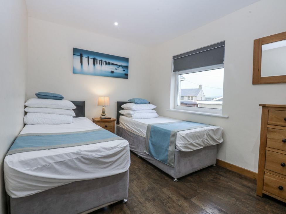 A bedroom with two beds and a nightstand at Benlli in Pwllheli