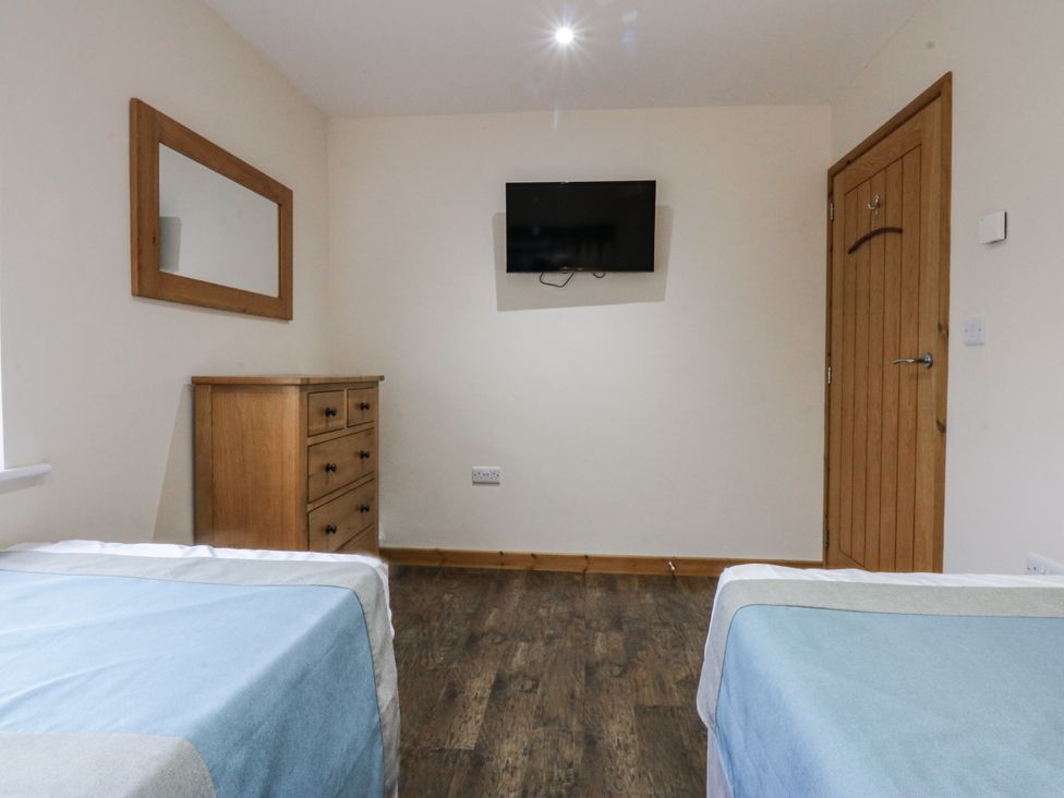 A bedroom with two beds and a dresser at Benlli in Pwllheli