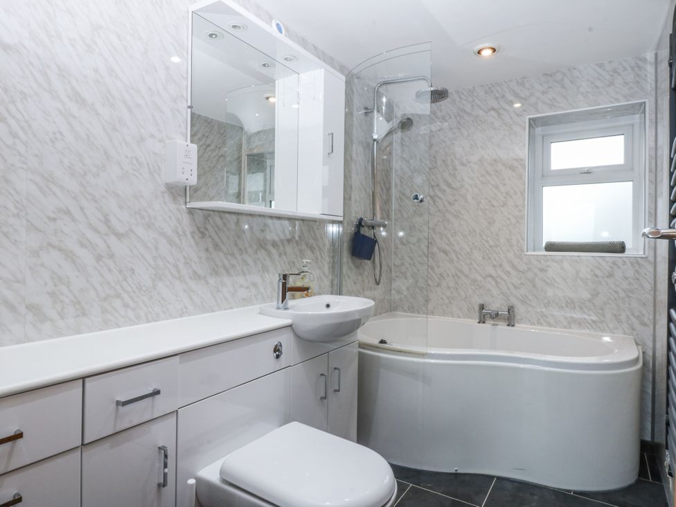 A bathroom with a bathtub, toilet, sink, and shower at Benlli in Pwllheli