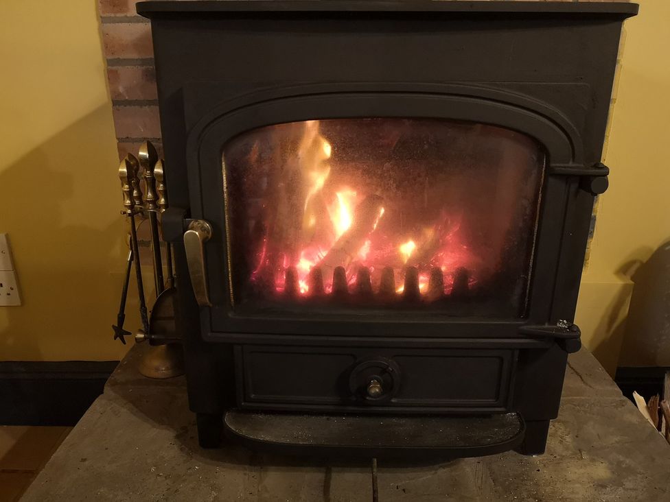 A fireplace with a wood stove and flames at Claymires Stirling