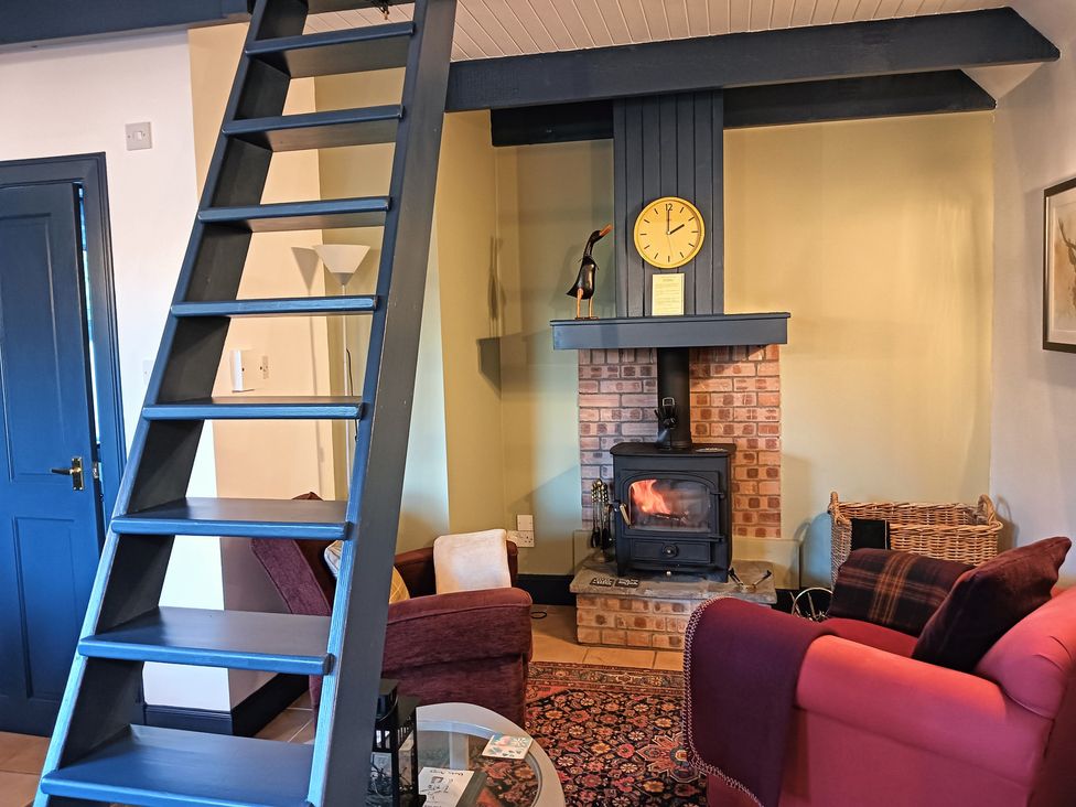 A living room with a fireplace and staircase at Claymires Stirling