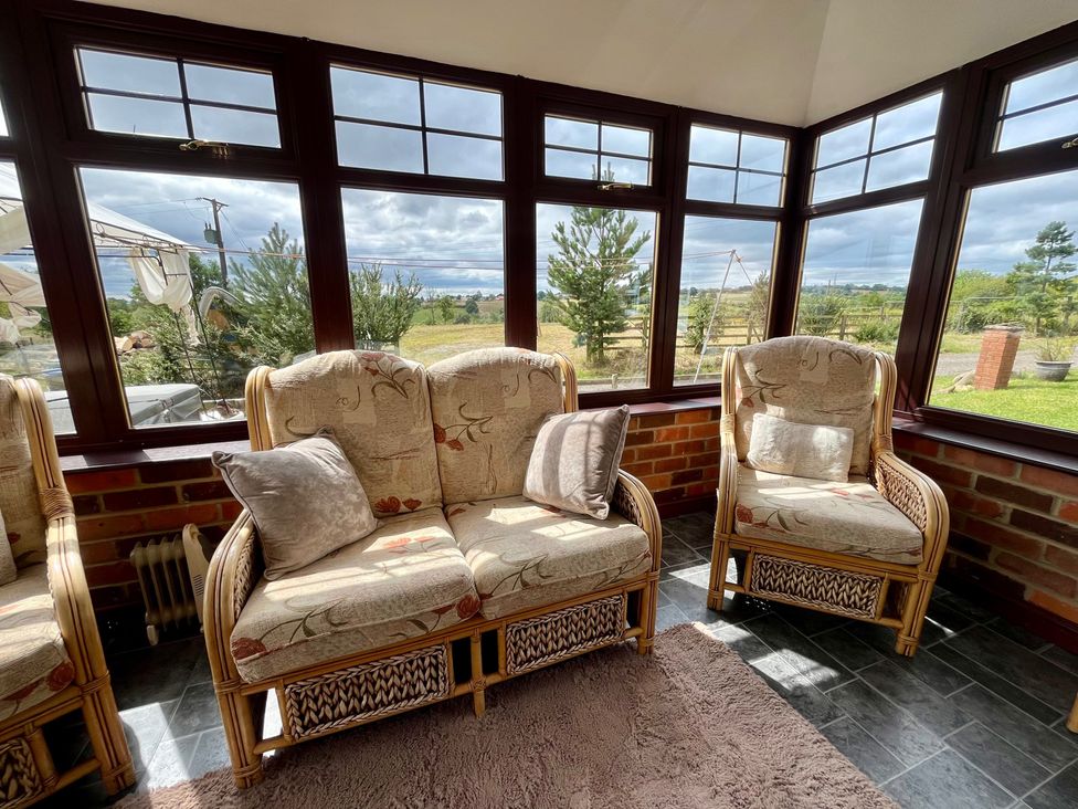 A conservatory with wicker sofas and large windows at Starshinezzz in Trimdon Station