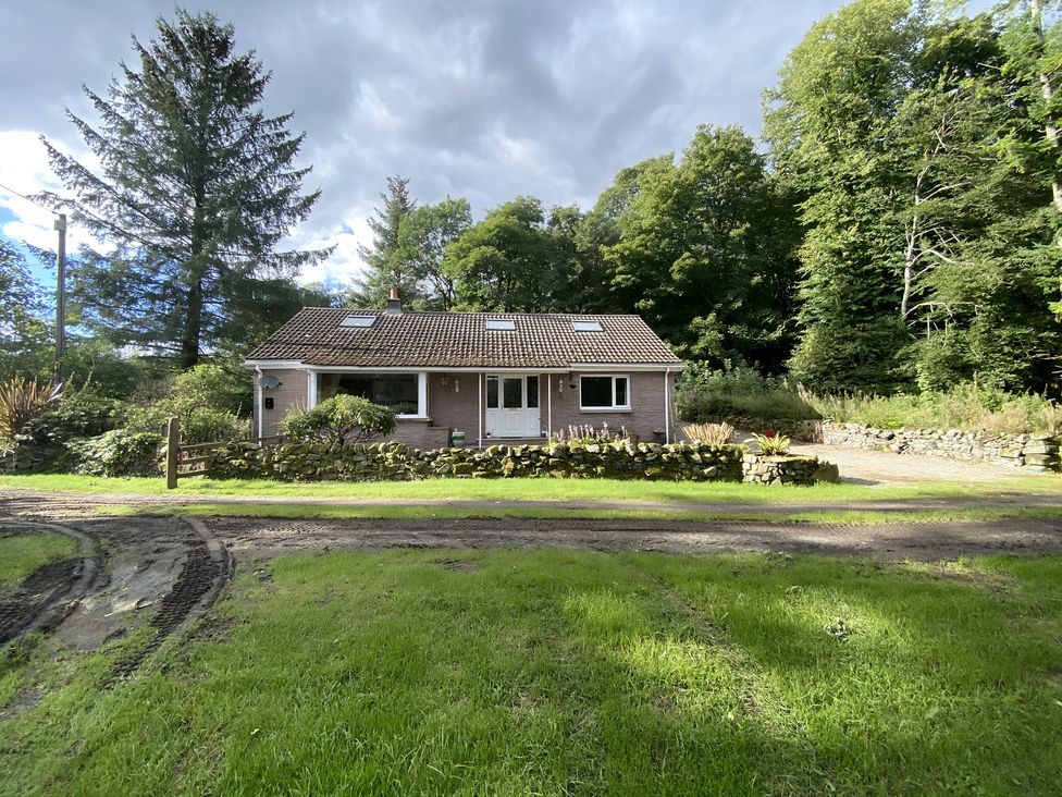 A house surrounded by trees and garden at Whispering Trees Cottage Thornhill