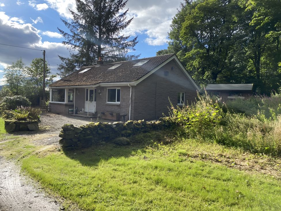 A house with trees and a stone wall at Whispering Trees Cottage in Thornhill