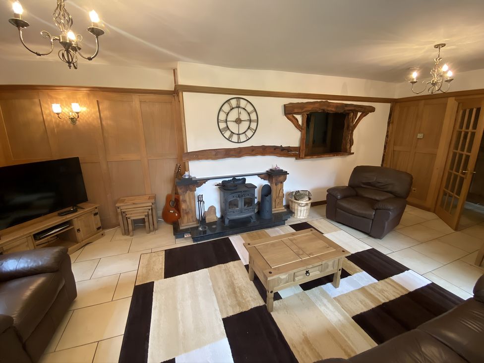 A living room with a sofa, coffee table, and wood stove at Whispering Trees Cottage in Thornhill