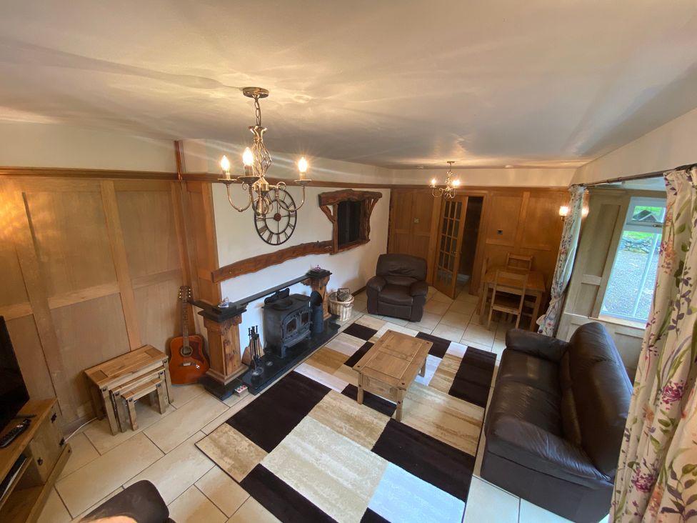 A living room with a wood stove and seating area at Whispering Trees Cottage in Thornhill