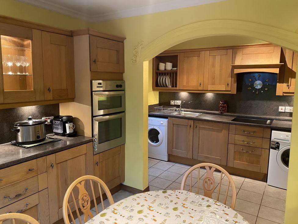 A kitchen with wooden cabinets and appliances at Whispering Trees Cottage in Thornhill