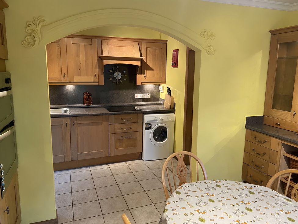 A kitchen with wooden cabinets and a table at Whispering Trees Cottage in Thornhill