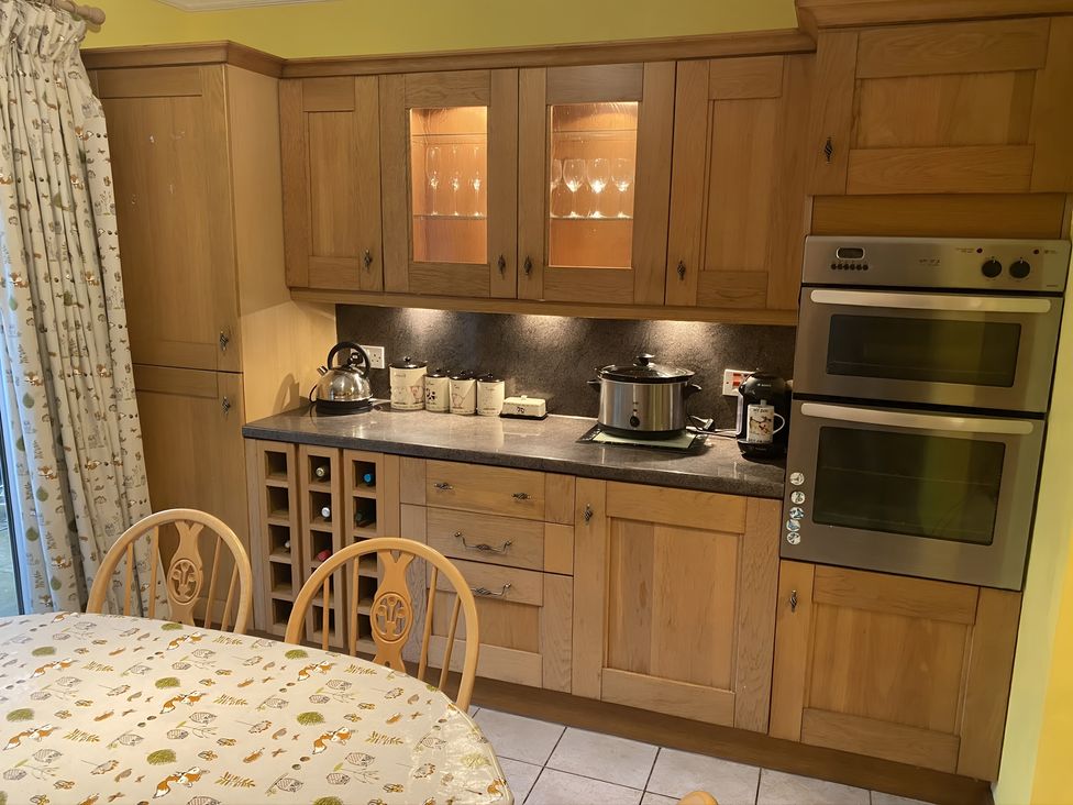 A kitchen with cabinets, kettle, slow cooker and wine rack at Whispering Trees Cottage in Thornhill