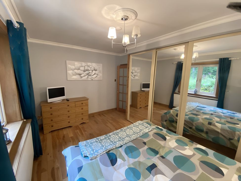 A bedroom with a bed, dresser, and television at Whispering Trees Cottage in Thornhill