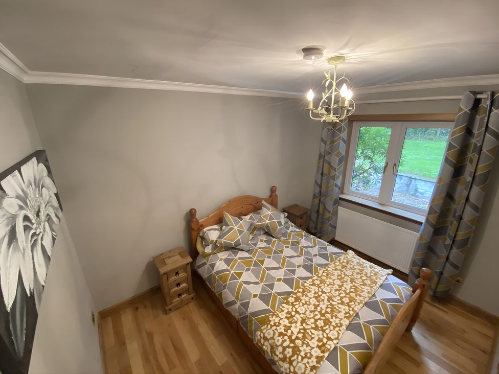 A bedroom with a bed and nightstands at Whispering Trees Cottage in Thornhill