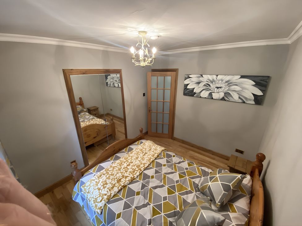 A bedroom with a bed and mirror at Whispering Trees Cottage in Thornhill