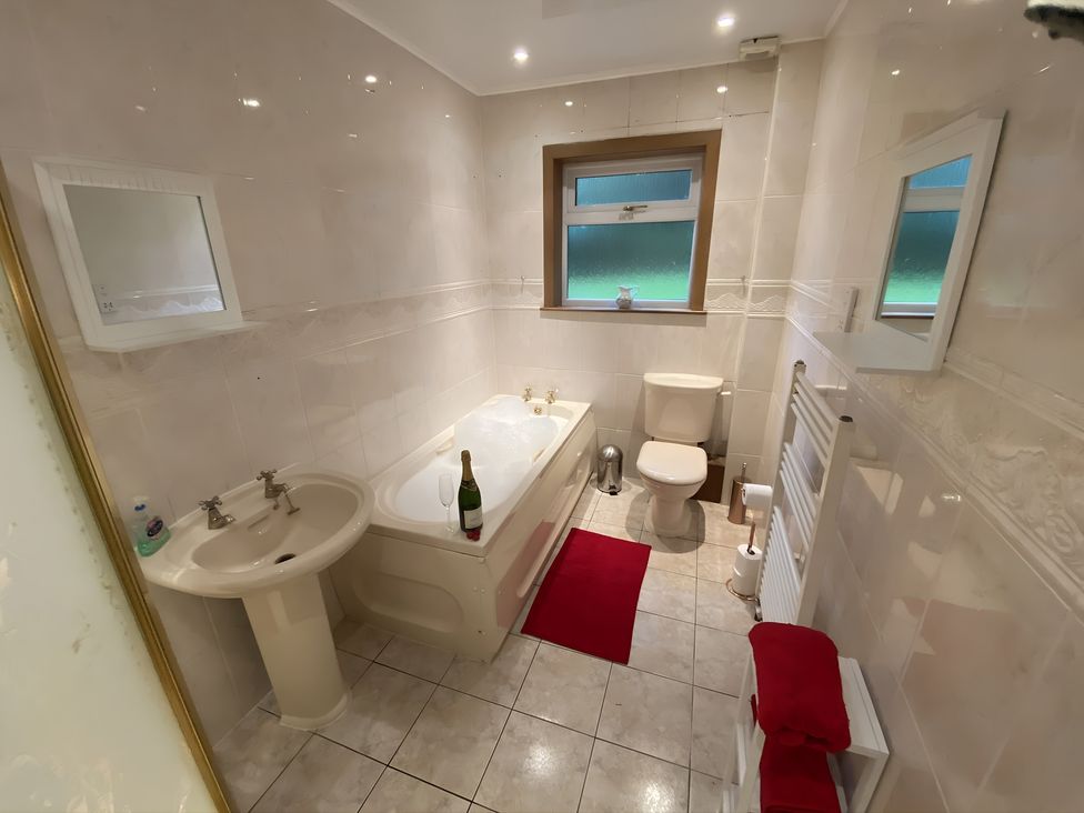 A bathroom with a bath tub, toilet, and sink at Whispering Trees Cottage Thornhill