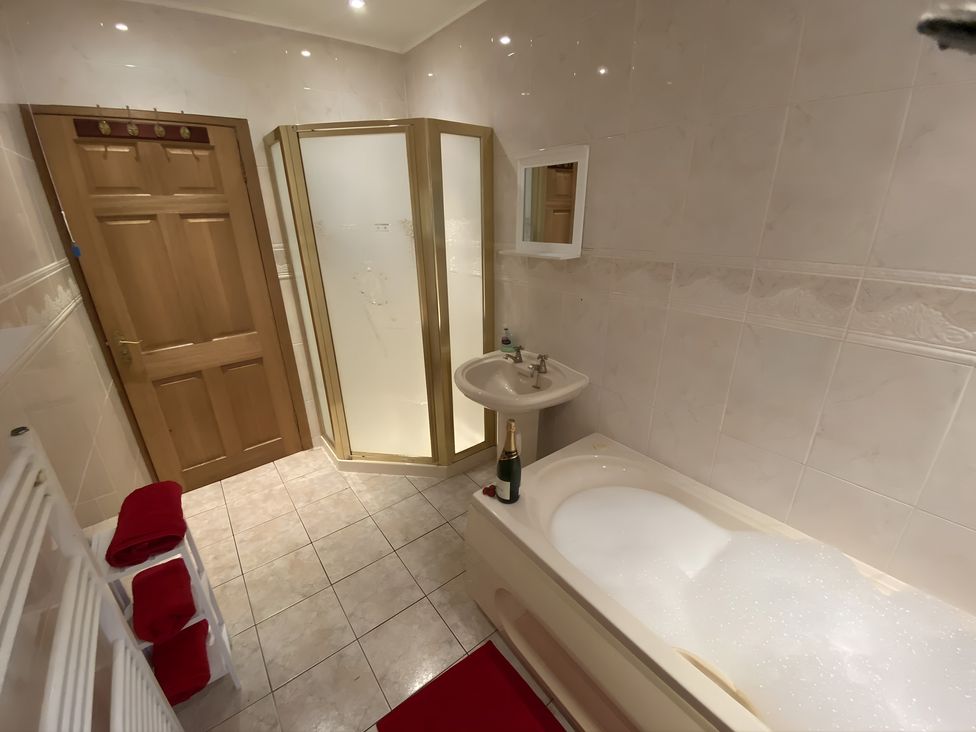A bathroom with a bathtub, shower, sink, and towels at Whispering Trees Cottage in Thornhill