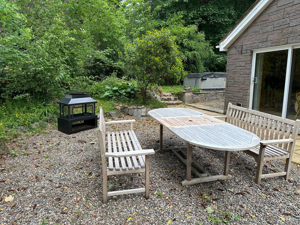 A garden with a table and benches at Whispering Trees Cottage in Thornhill