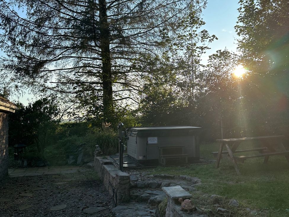 A garden with a hot tub and picnic table at Whispering Trees Cottage in Thornhill