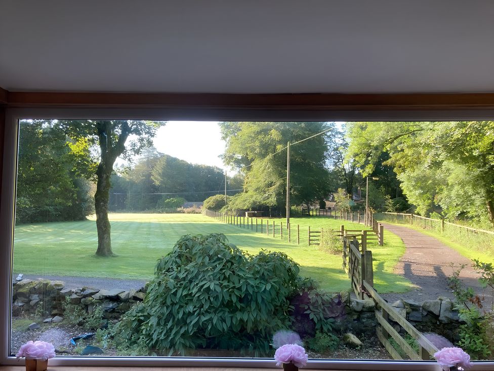 A view of a grassy field with trees and a pathway at Whispering Trees Cottage in Thornhill