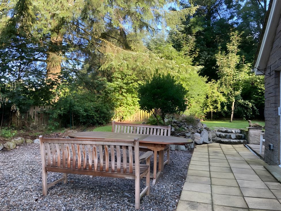 A garden with a table and benches at Whispering Trees Cottage in Thornhill