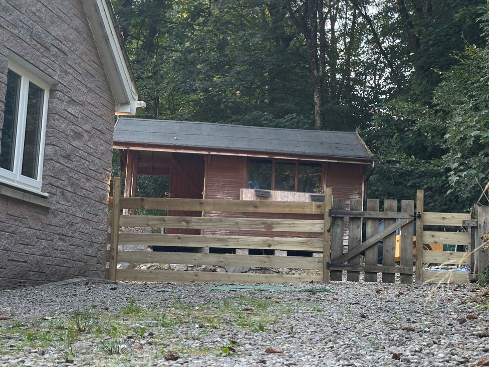 A yard with a house, a shed, and wooden fence at Whispering Trees Cottage in Thornhill