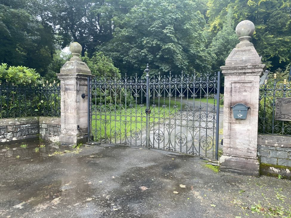 A gate with stone pillars and a mailbox at Whispering Trees Cottage in Thornhill