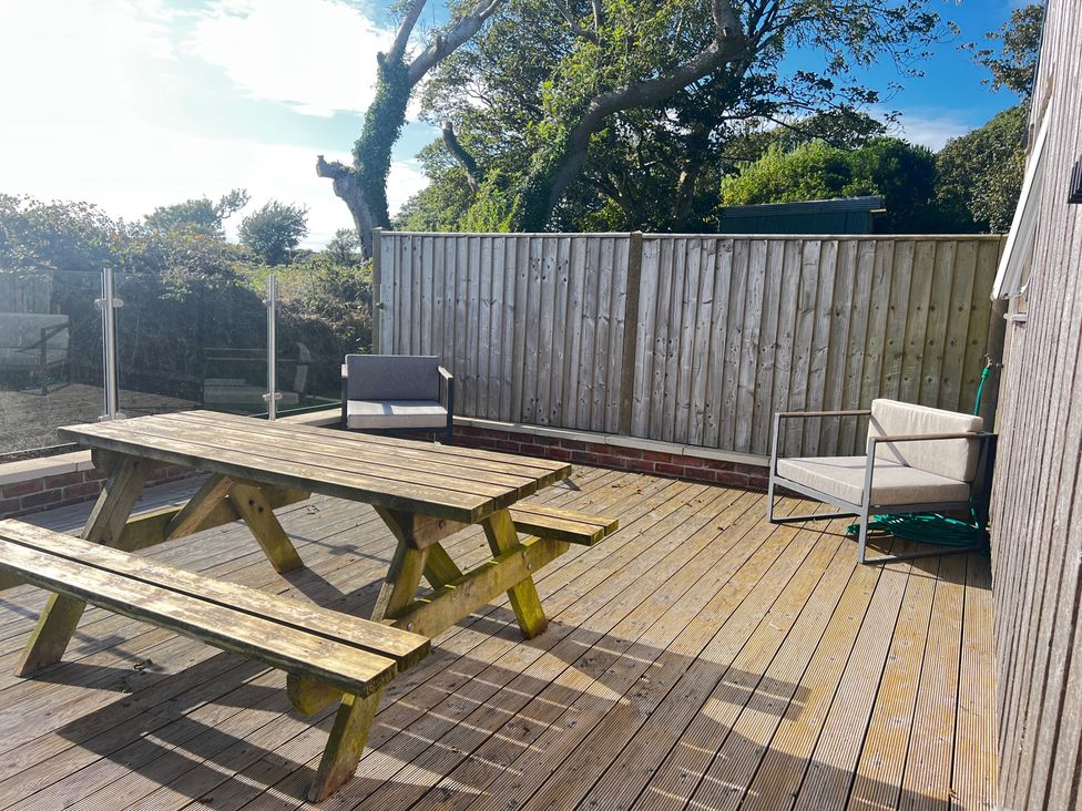 An outdoor seating area with a wooden table and chairs at The lodge at Plumstone View Haverfordwest