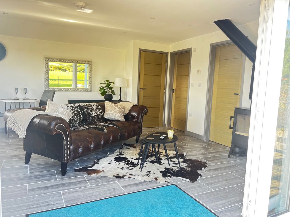 A living room with a sofa, coffee table, and a fireplace at The lodge at Plumstone View in Haverfordwest