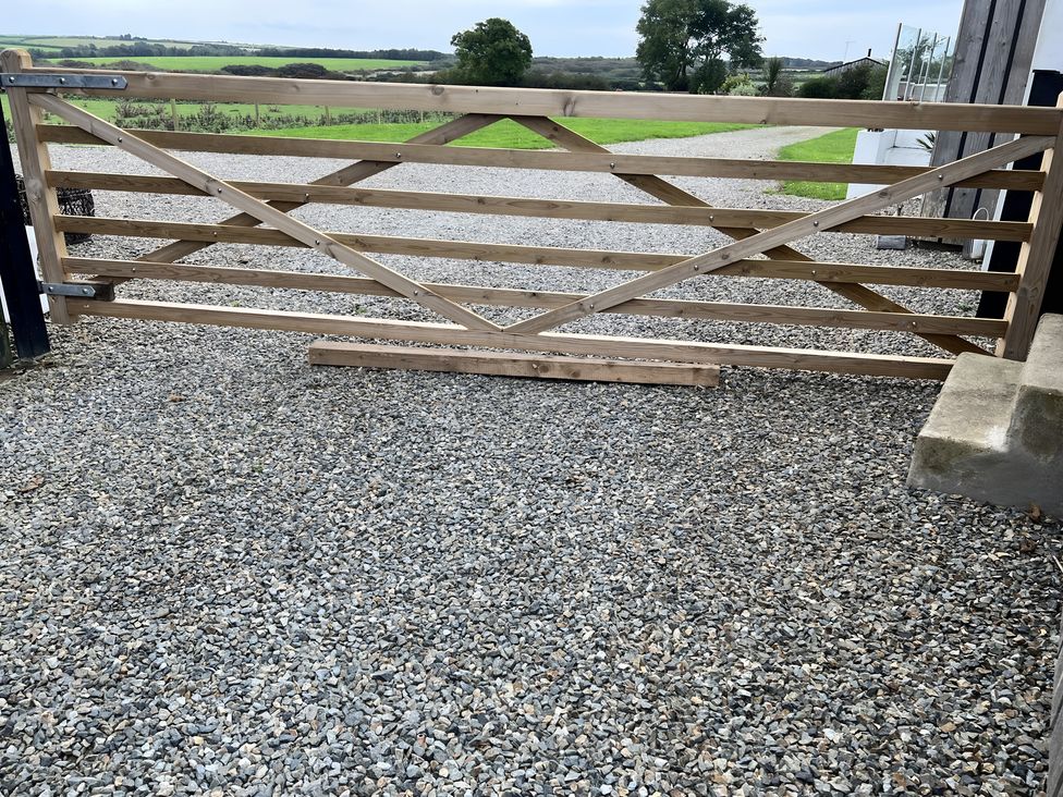 A wooden gate on gravel leading to a field at The lodge at Plumstone View in Haverfordwest