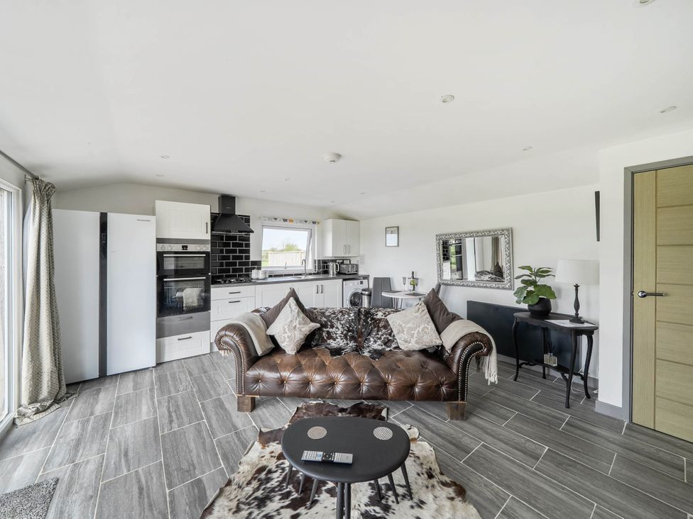 A living room with a couch and kitchen appliances at The lodge at Plumstone View in Letterston