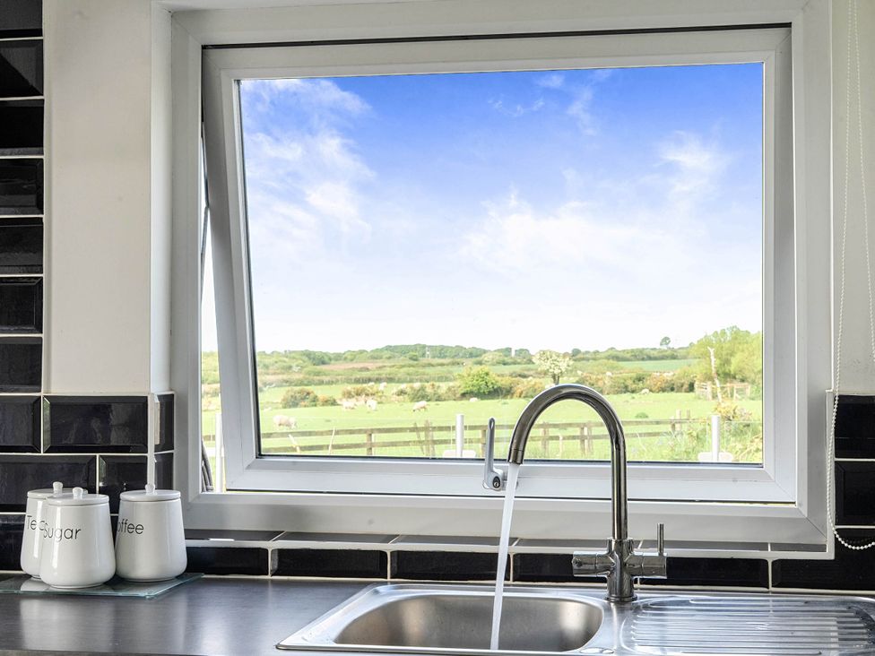 A kitchen sink with jars and a window at The lodge at Plumstone View in Letterston