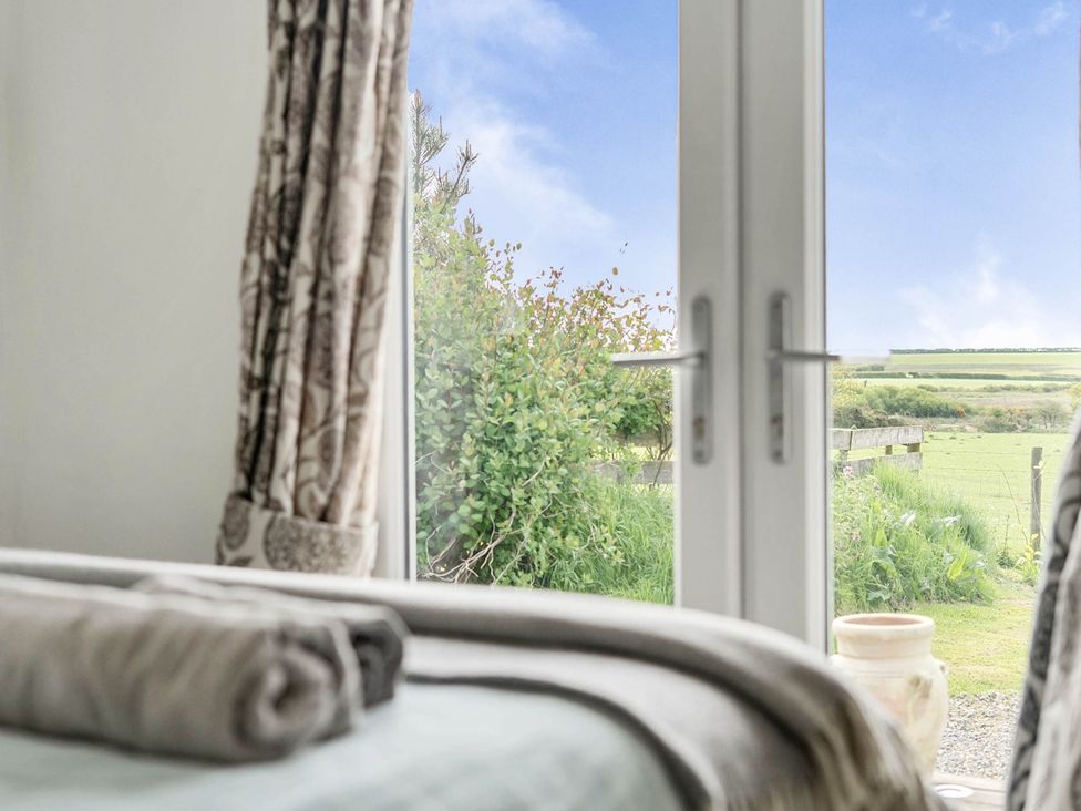 A view from a bedroom window with curtains and towels at The lodge at Plumstone View in Letterston