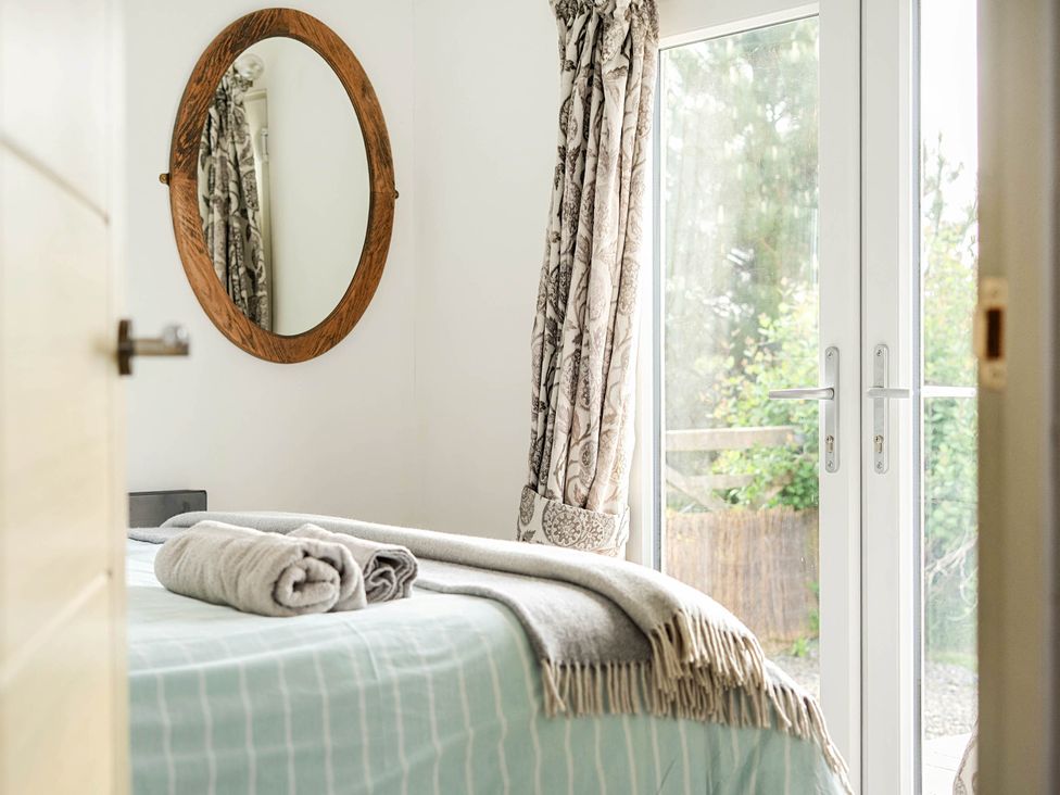 A bedroom with a bed and a mirror at The lodge at Plumstone View Letterston