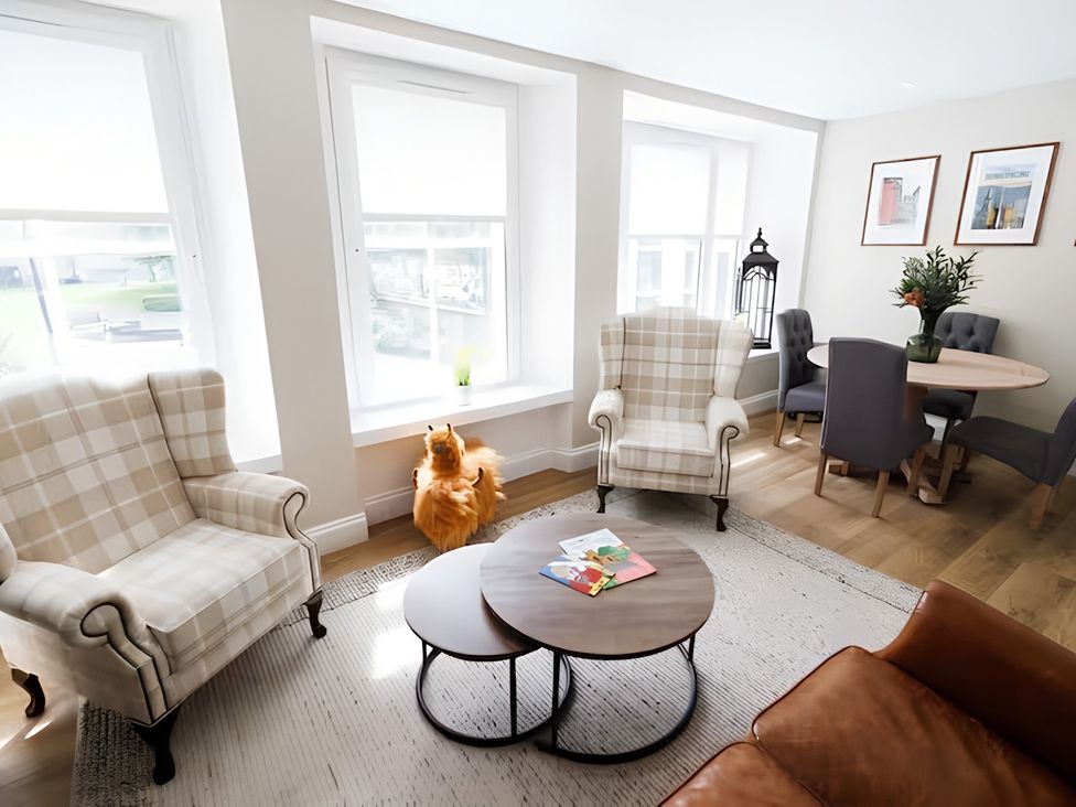 A living room with armchairs and a dining table at Robert the Bruce Apartment in Dunfermline